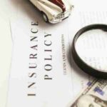 Close-up image of an insurance policy with a magnifying glass, money, and toy car., tags: zu - pexel